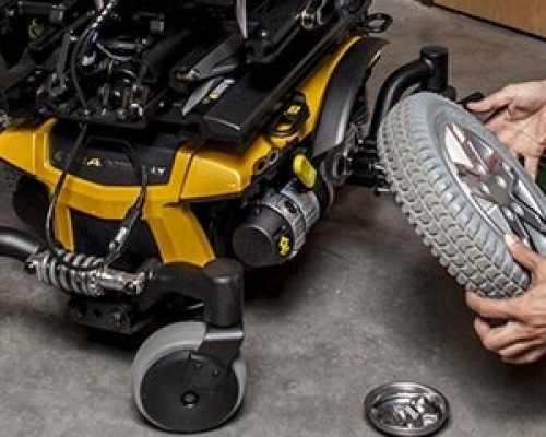 A power wheelchair undergoing repairs to the wheels