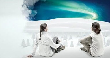 Two people overlooking a snowy landscape with northern lights