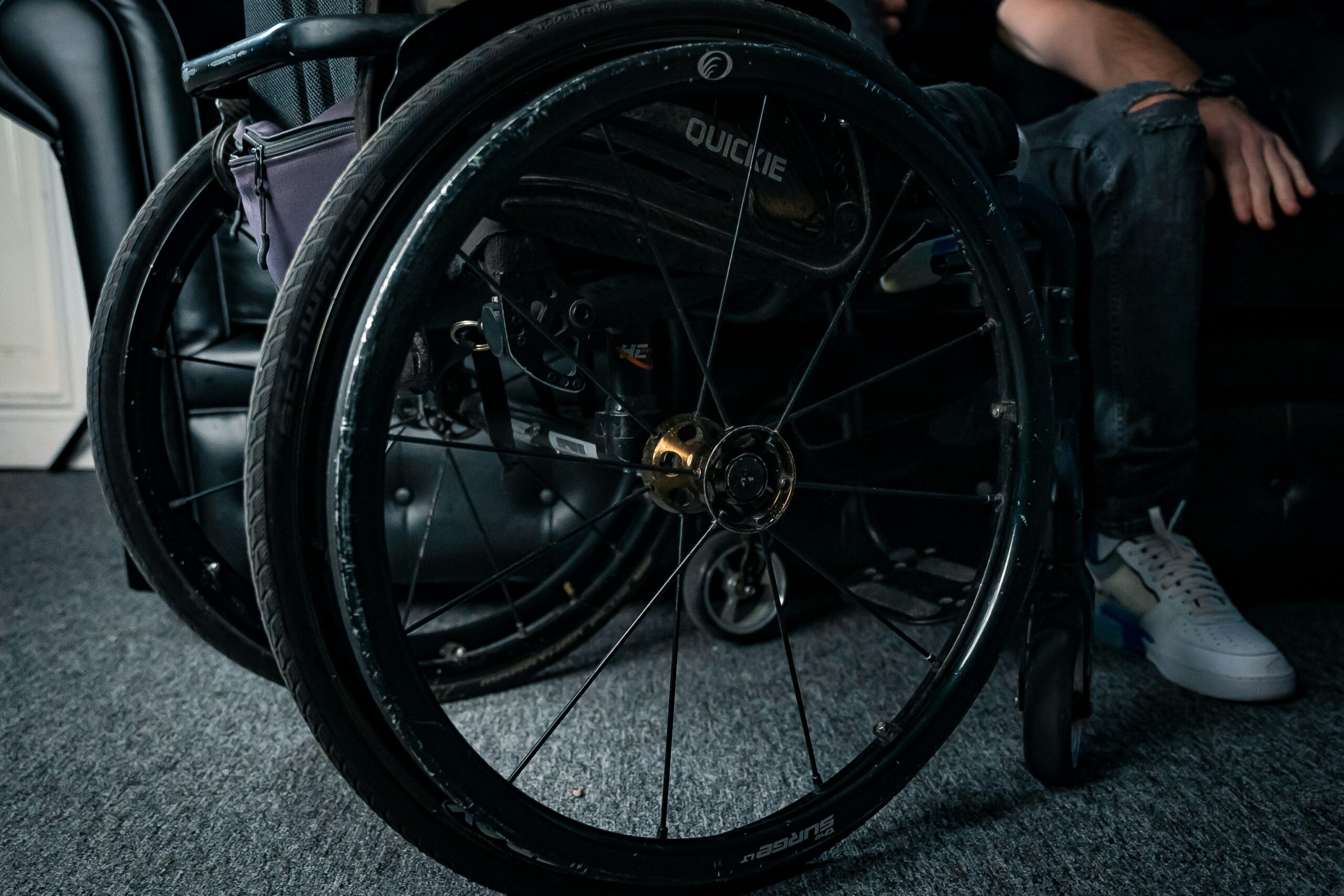 A dark photo of a wheelchair with the focus on the wheel.